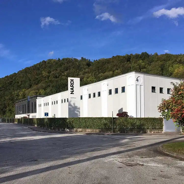 Weißes Nardi-Gebäude mit grüner Efeu und blauem Himmel im Hintergrund.