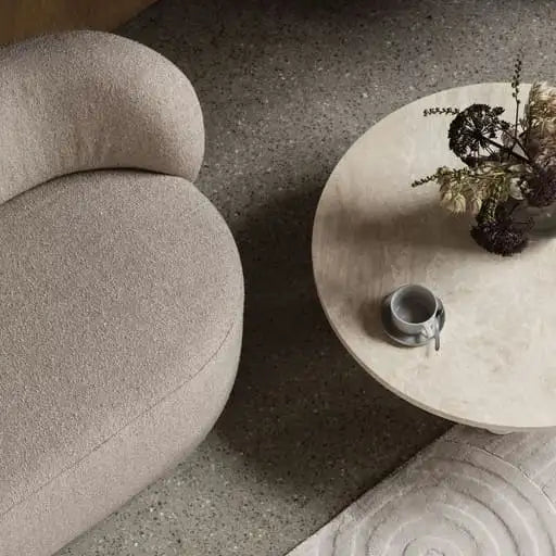 Beige, mit Plüsch bezogener Sessel mit abgerundeten Konturen.