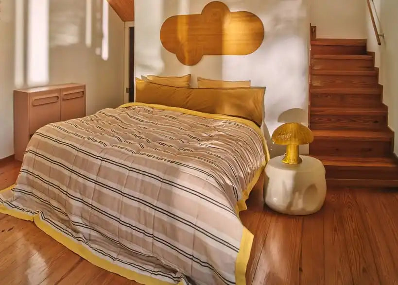 Ein Bett mit einer gestreiften Bettdecke und gelben Besatz.