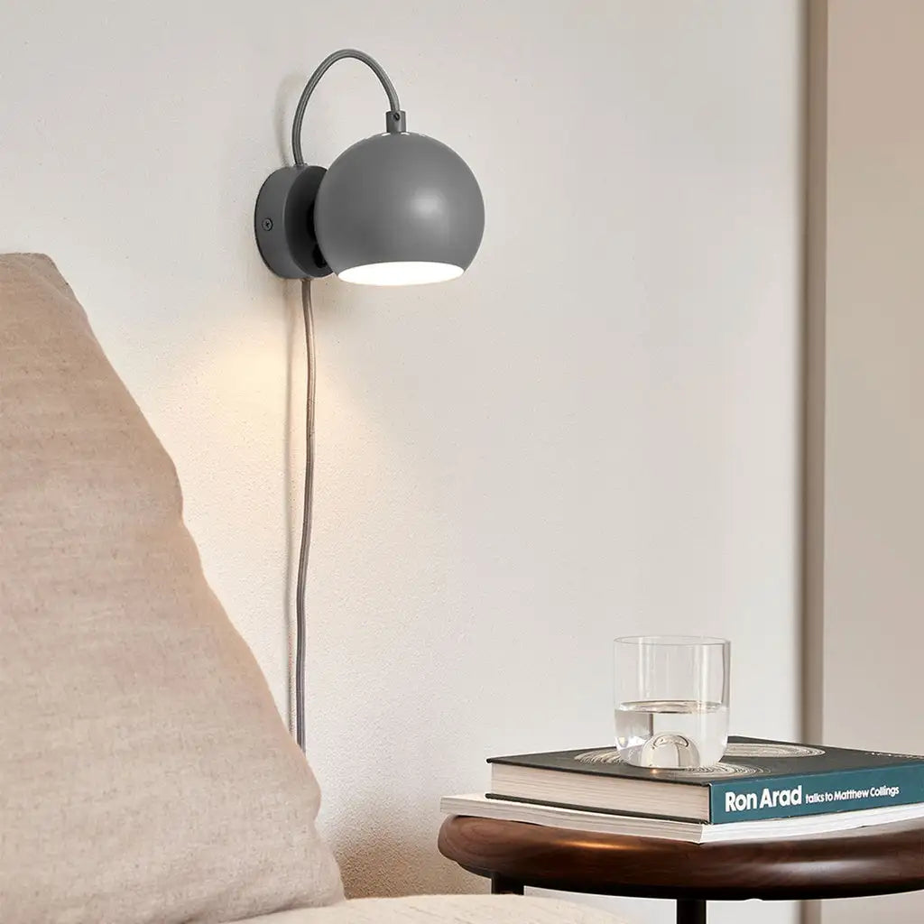 Moderne graue sphärische Wandlampe mit einem gebogenen metallischen Arm und freiliegendem Kabel.