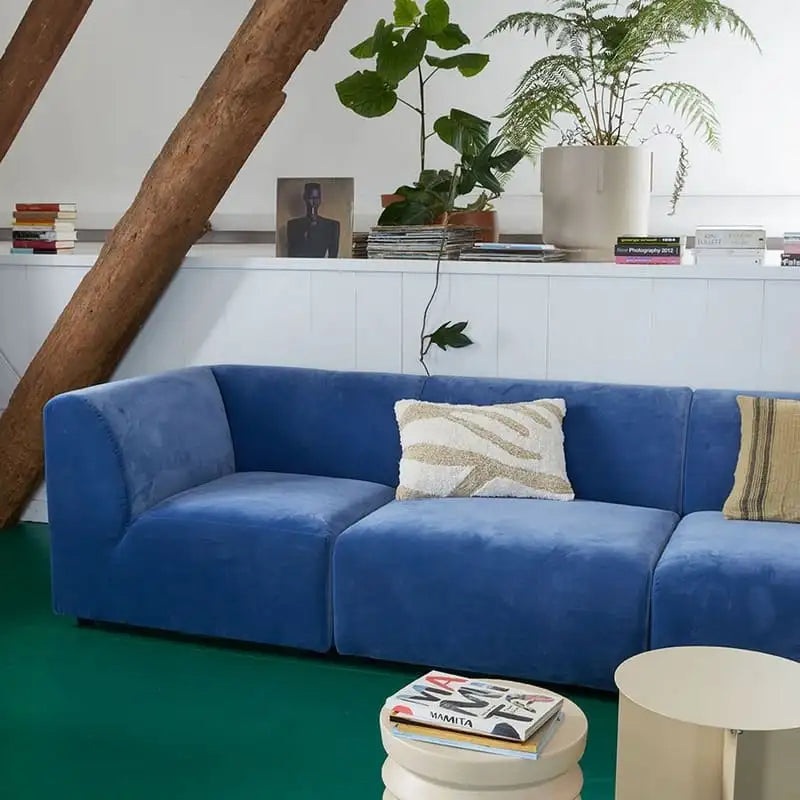 Ein plüschiger königsblauer Samtsofa mit modernem, modularen Design und zwei dekorativen Kissen.